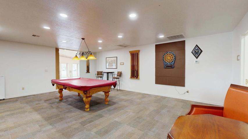 Spacious recreation room featuring recessed lighting, carpet flooring, and a large open doorway