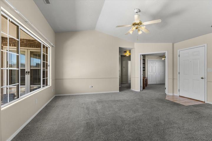 Spacious room featuring vaulted ceilings, a large multi-pane window, and neutral-toned carpeting