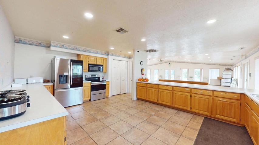 Spacious kitchen featuring extensive counter space, light wood cabinetry, stainless steel appliances, tile flooring, and recessed lighting