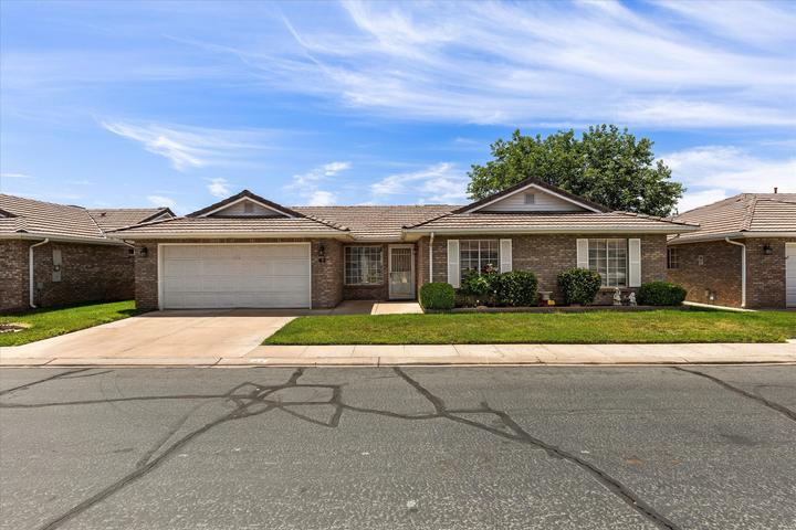Brick exterior featuring a two-car garage, concrete driveway, and front lawn