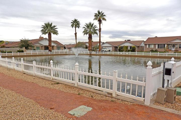 Water feature with a central fountain, white picket fence, and a gravel pathway