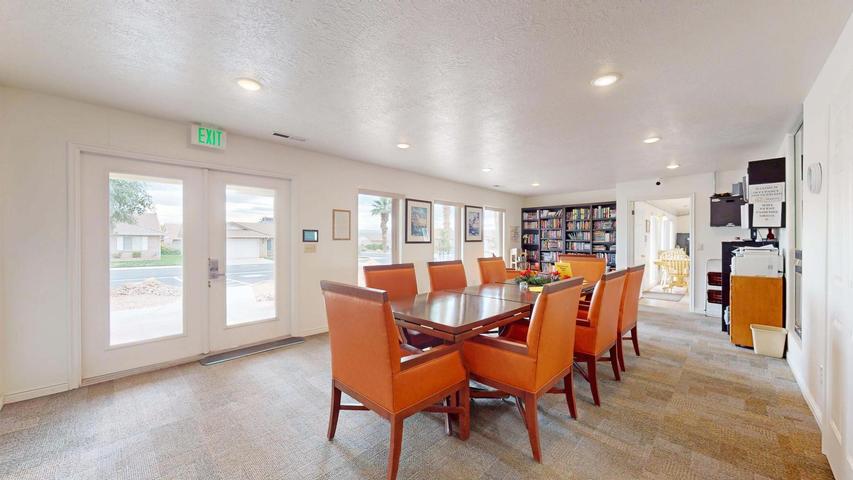 Spacious community room featuring a large rectangular table with seating for eight, recessed ceiling lighting, and durable carpet flooring