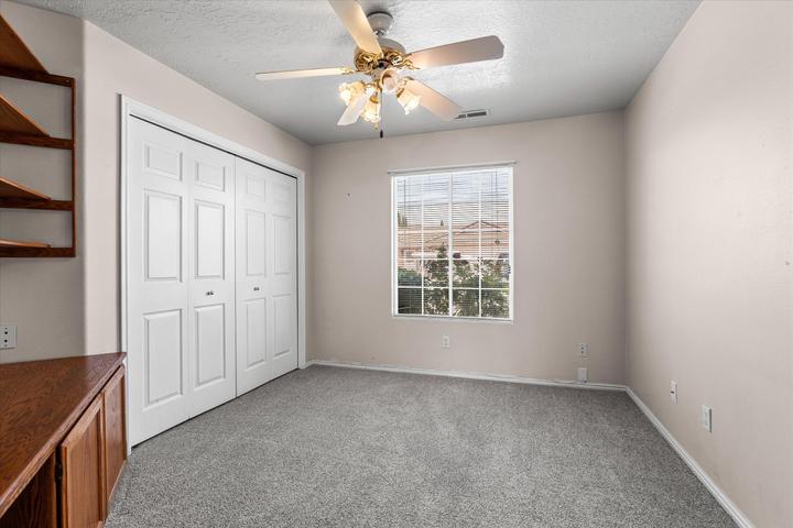 Spacious room featuring neutral-toned walls, grey carpeting, and a multi-pane window with blinds