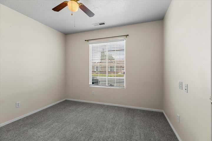 Neutral-toned interior room featuring light gray carpeting, white baseboards, and a single window with horizontal blinds