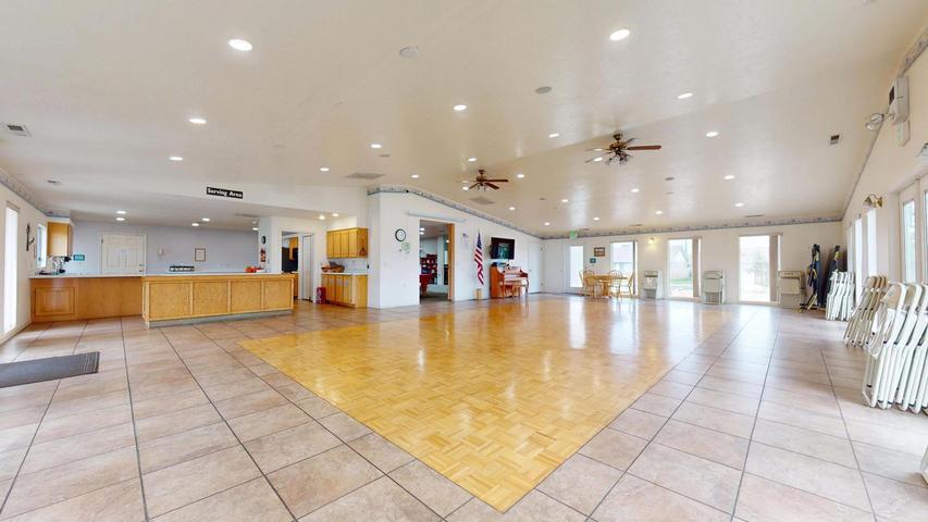 Spacious multi-purpose room featuring a large wood-finish dance floor area and surrounding tile flooring