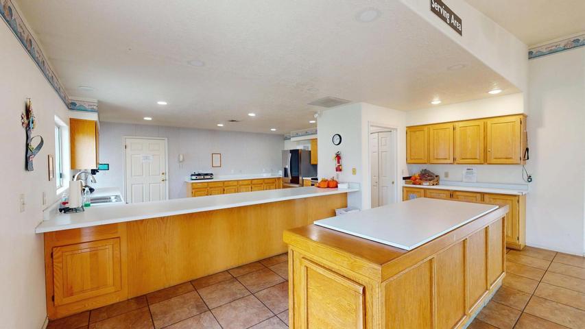 Spacious kitchen featuring light wood cabinetry, white countertops, a central island, recessed lighting, and tile flooring