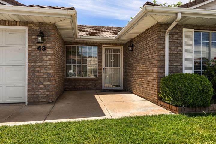 Brick exterior featuring a concrete entryway and manicured lawn