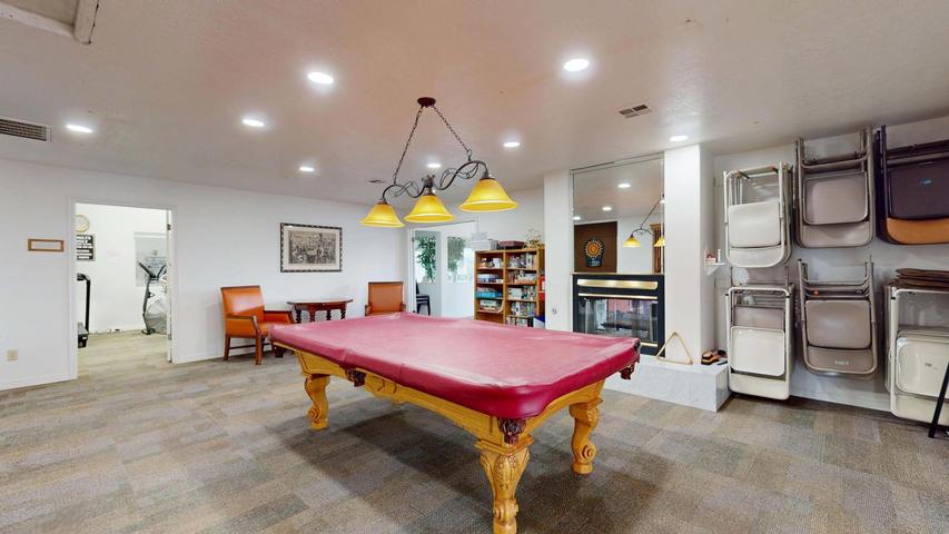 Spacious recreation area featuring a built-in fireplace, patterned tile flooring, recessed lighting, and a decorative chandelier