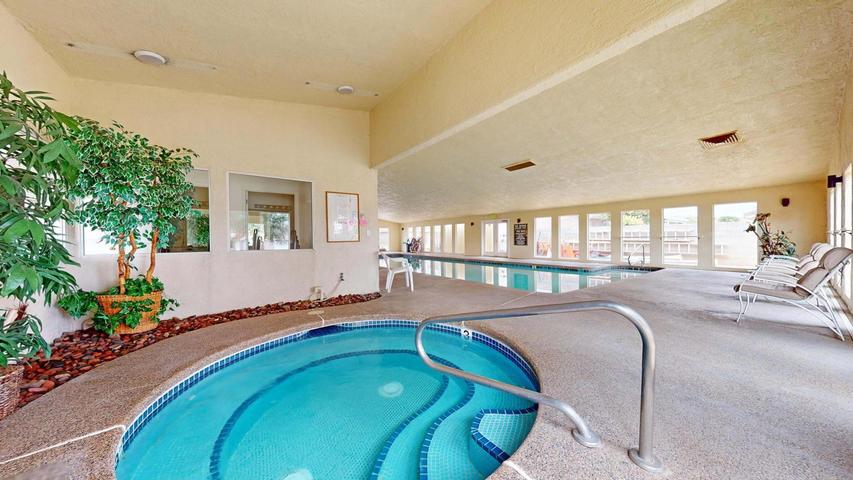 Indoor aquatic center featuring a spa with mosaic tile accents and an adjacent lap pool