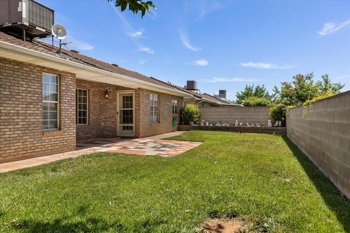 Expansive backyard featuring a manicured lawn, a tiled patio, and mature block wall fencing