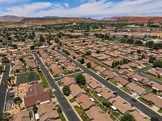 Aerial perspective showcasing a residential community with uniform roofing and established landscaping, set against a backdrop of red rock formations