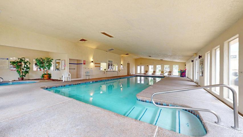 Indoor swimming pool featuring an integrated hot tub and tiled coping
