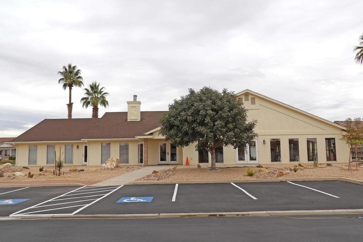 Exterior building with a light stucco finish, brown shingle roof, and multiple large windows