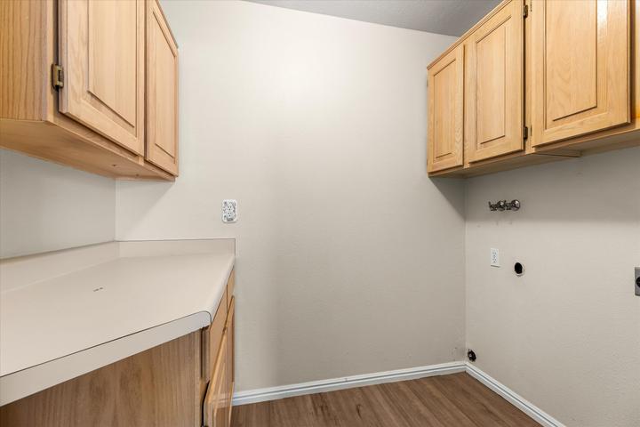 Utility room featuring wood-finish flooring, ample cabinetry, and countertop space