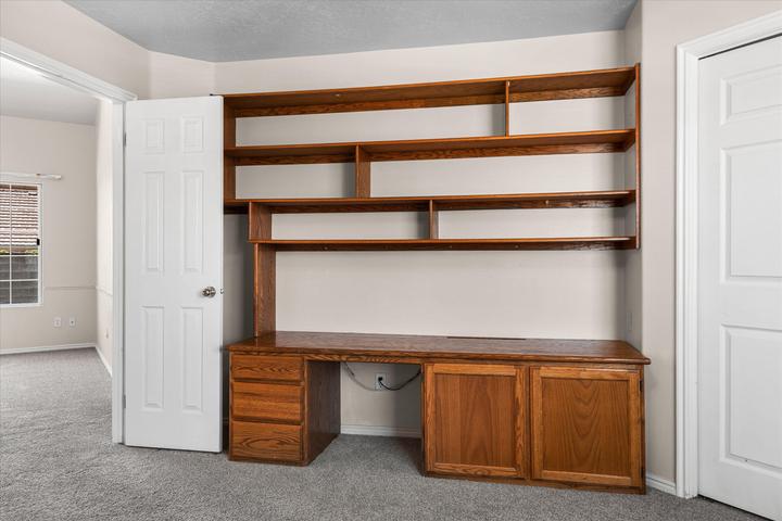 Built-in wood-finish desk with integrated shelving, drawer storage, and cabinet storage