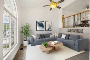 Spacious living area featuring a vaulted ceiling with a ceiling fan, a large arch-top window, a carpeted floor, and a half-wall with decorative tile inlay and a wooden railing with wrought iron balusters