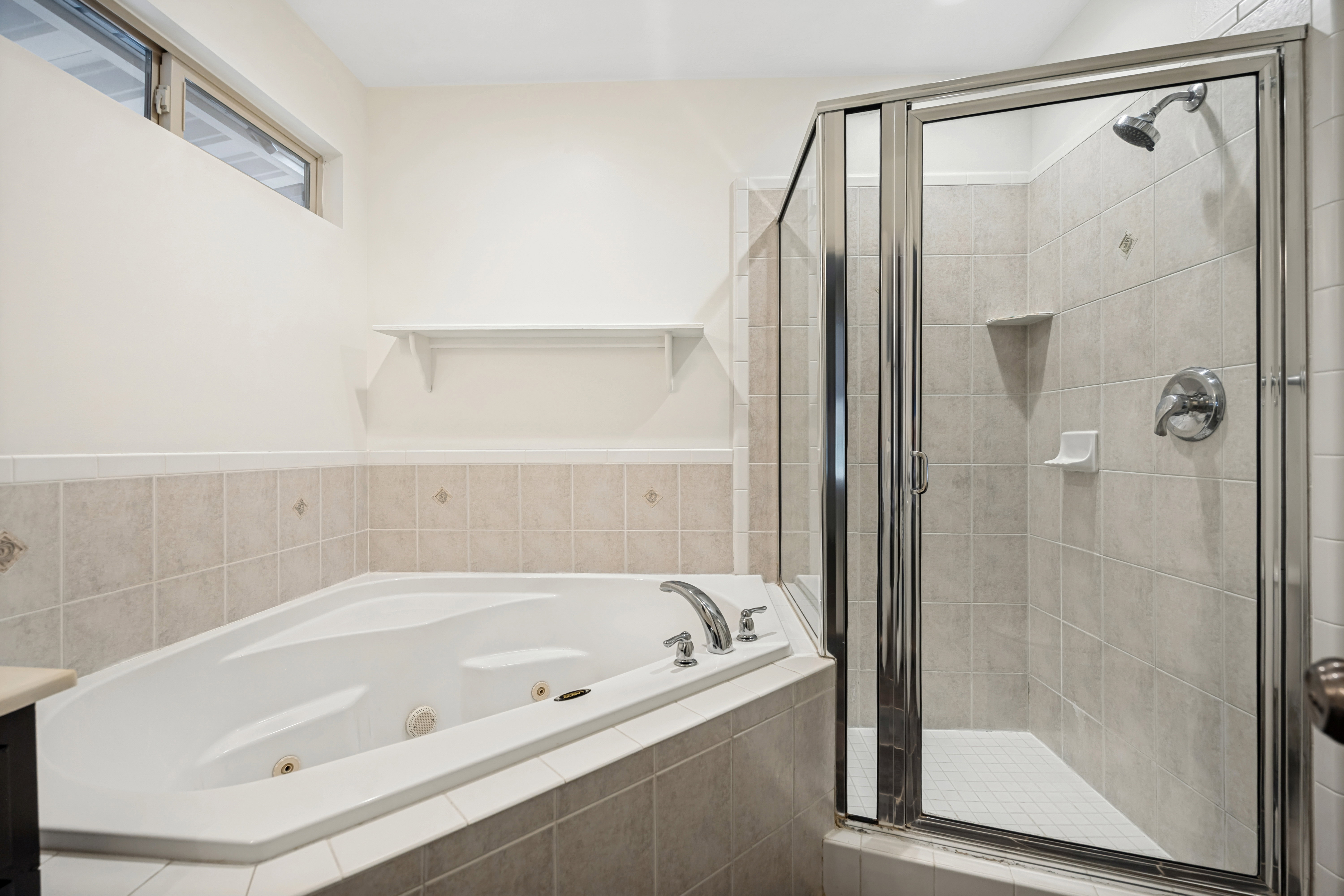 Bathroom featuring a corner jetted soaking tub and a separate glass-enclosed shower