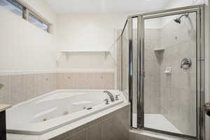 Bathroom featuring a corner jetted soaking tub and a separate glass-enclosed shower
