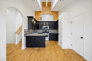 Kitchen featuring dark cabinetry, light-toned countertops, a full suite of stainless steel appliances, and a mosaic tile backsplash