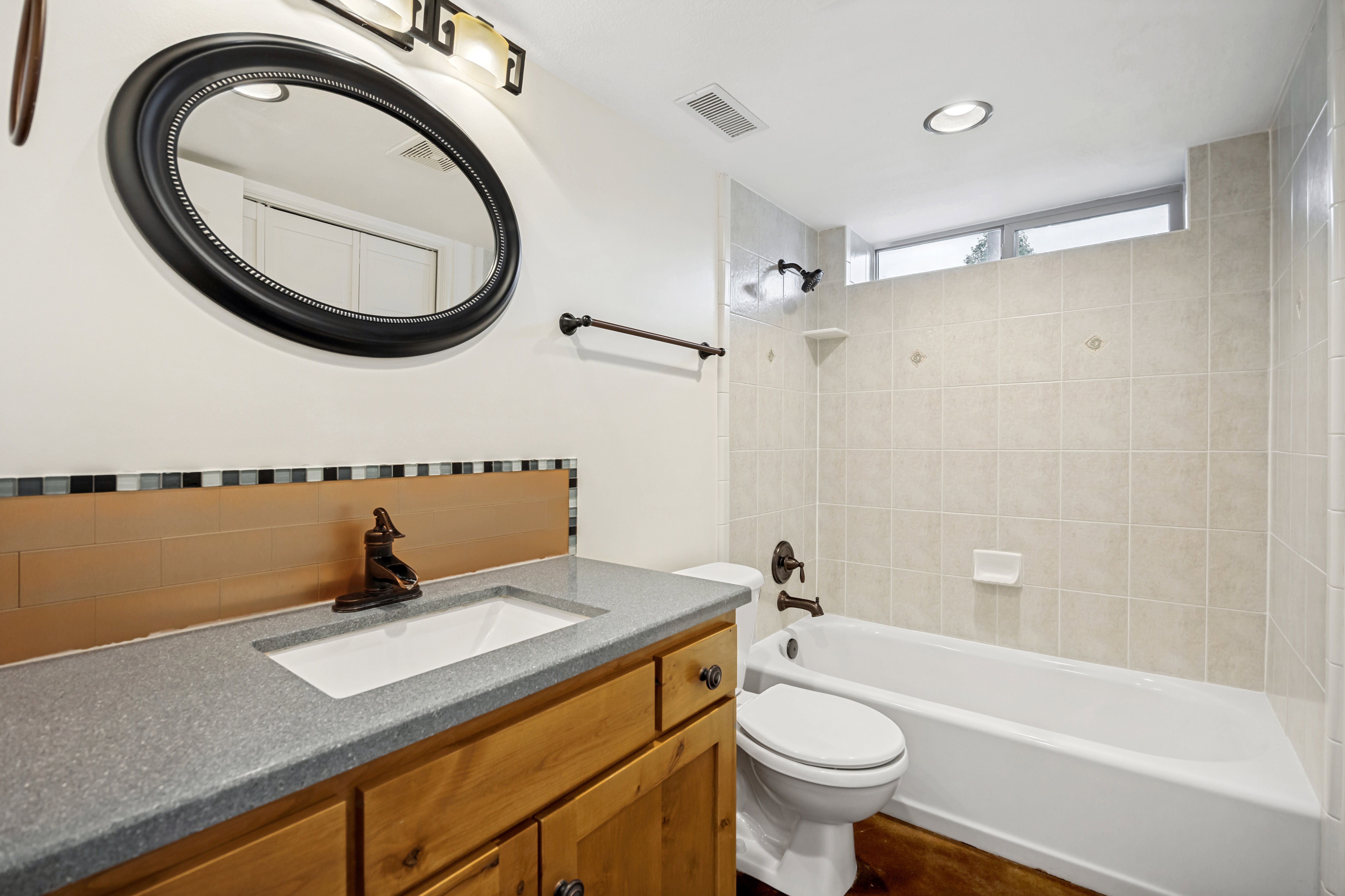 Bathroom featuring a wood-finish vanity with a grey speckled countertop and an undermount sink