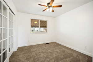 Spacious room featuring white walls, brown carpet, a window, and a ceiling fan with integrated lighting