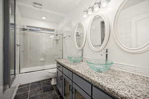 Dual vessel sinks set atop a granite-style countertop and gray cabinetry