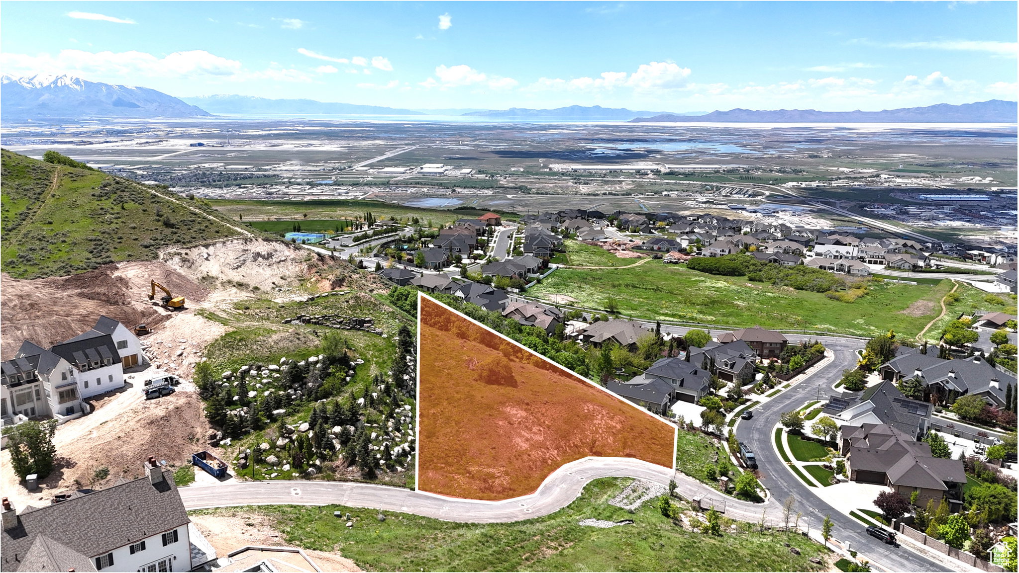 Sloping hillside parcel with surrounding residential development and paved road frontage