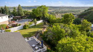 Tiered backyard featuring multiple outdoor living spaces, mature landscaping, and a white picket fence