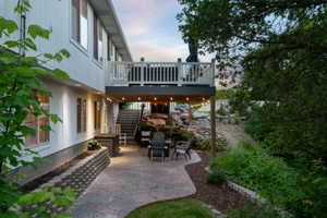 Expansive stamped concrete patio featuring string lighting, terraced landscaping with natural rock elements, and a concrete block retaining wall