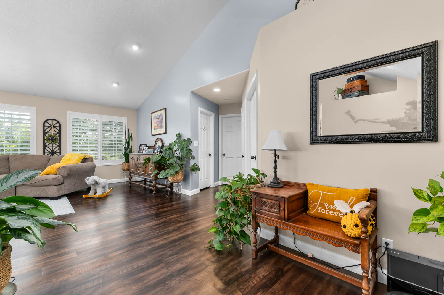 Spacious living area featuring wood-finish flooring, vaulted ceilings, and recessed lighting