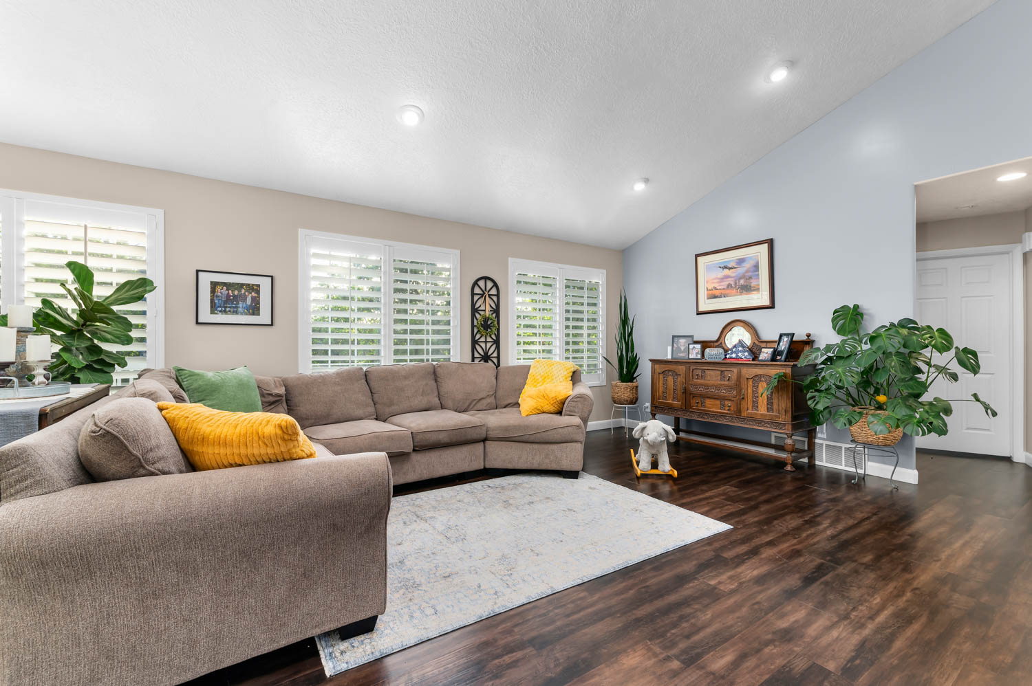 Spacious living area featuring wood-finish flooring, vaulted ceilings, and recessed lighting