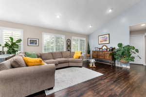 Spacious living area featuring wood-finish flooring, vaulted ceilings, and recessed lighting