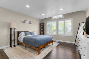 Spacious room featuring dark wood-finish flooring, recessed lighting, and a vaulted ceiling