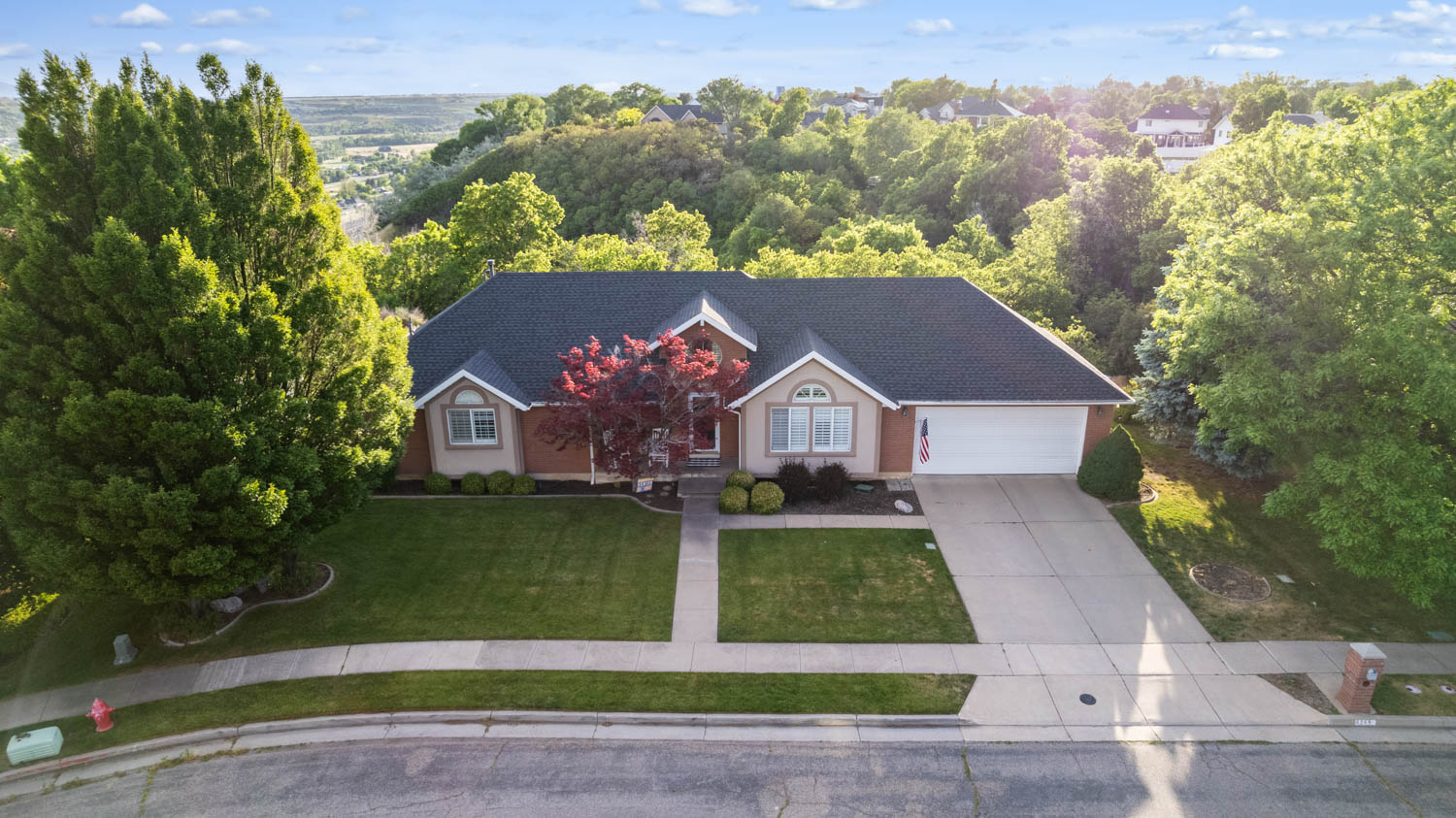 Traditional-style home featuring a dark shingle roof, light brick exterior, and an attached two-car garage