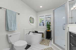 Contemporary bathroom featuring a freestanding tub, glass-enclosed shower, rectangular window with plantation shutters, circular accent window, and white tile flooring