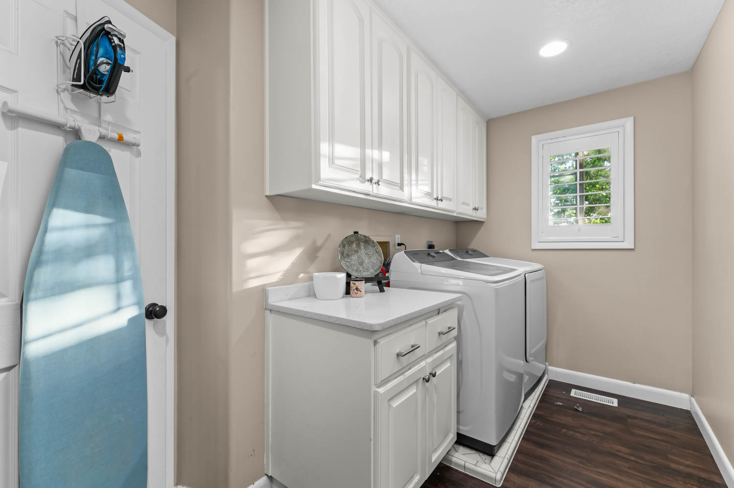 Utility space featuring white cabinetry, a white countertop, and dark wood-finish flooring