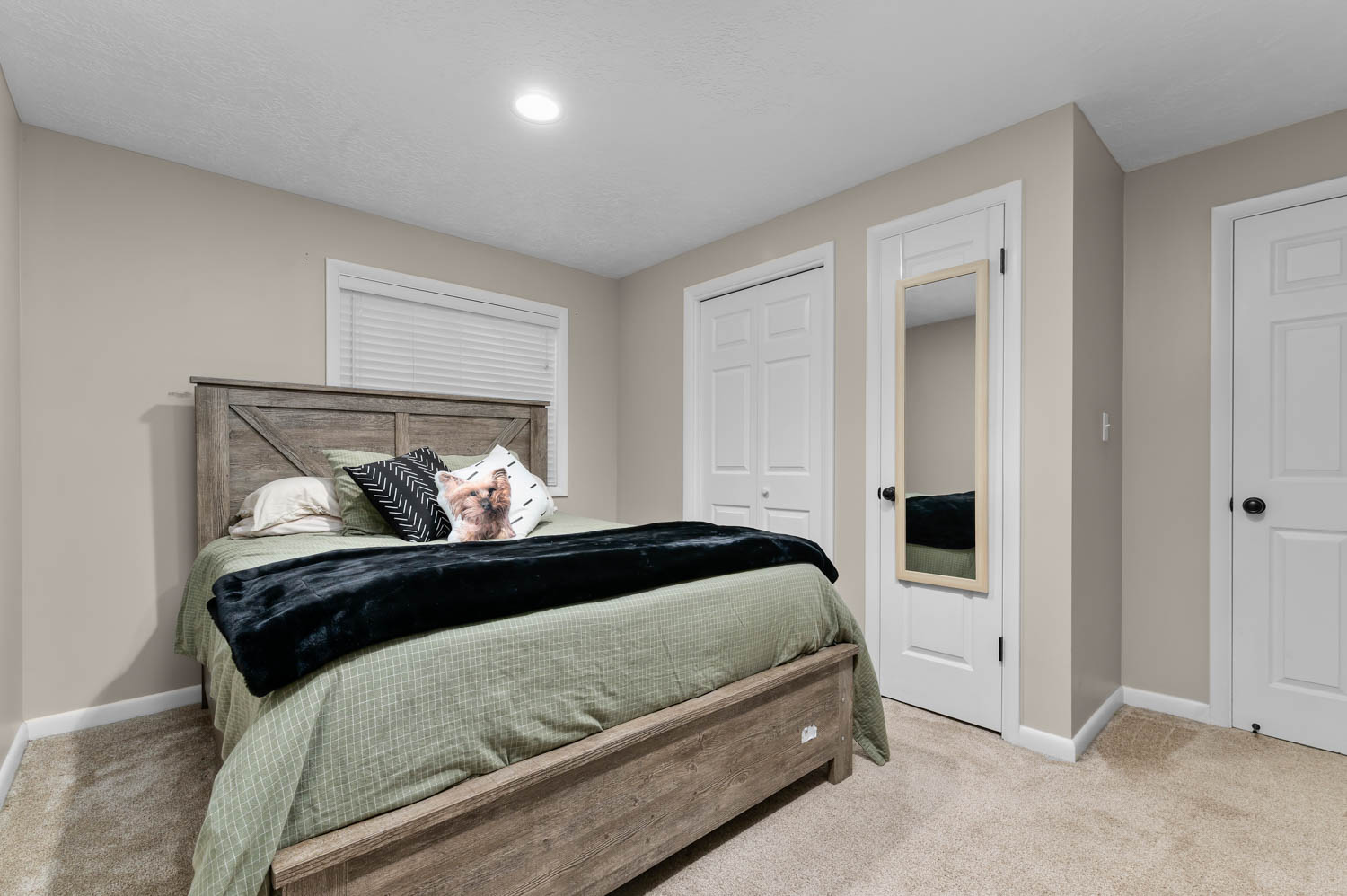 Carpeted room with neutral wall tones and a window featuring blinds