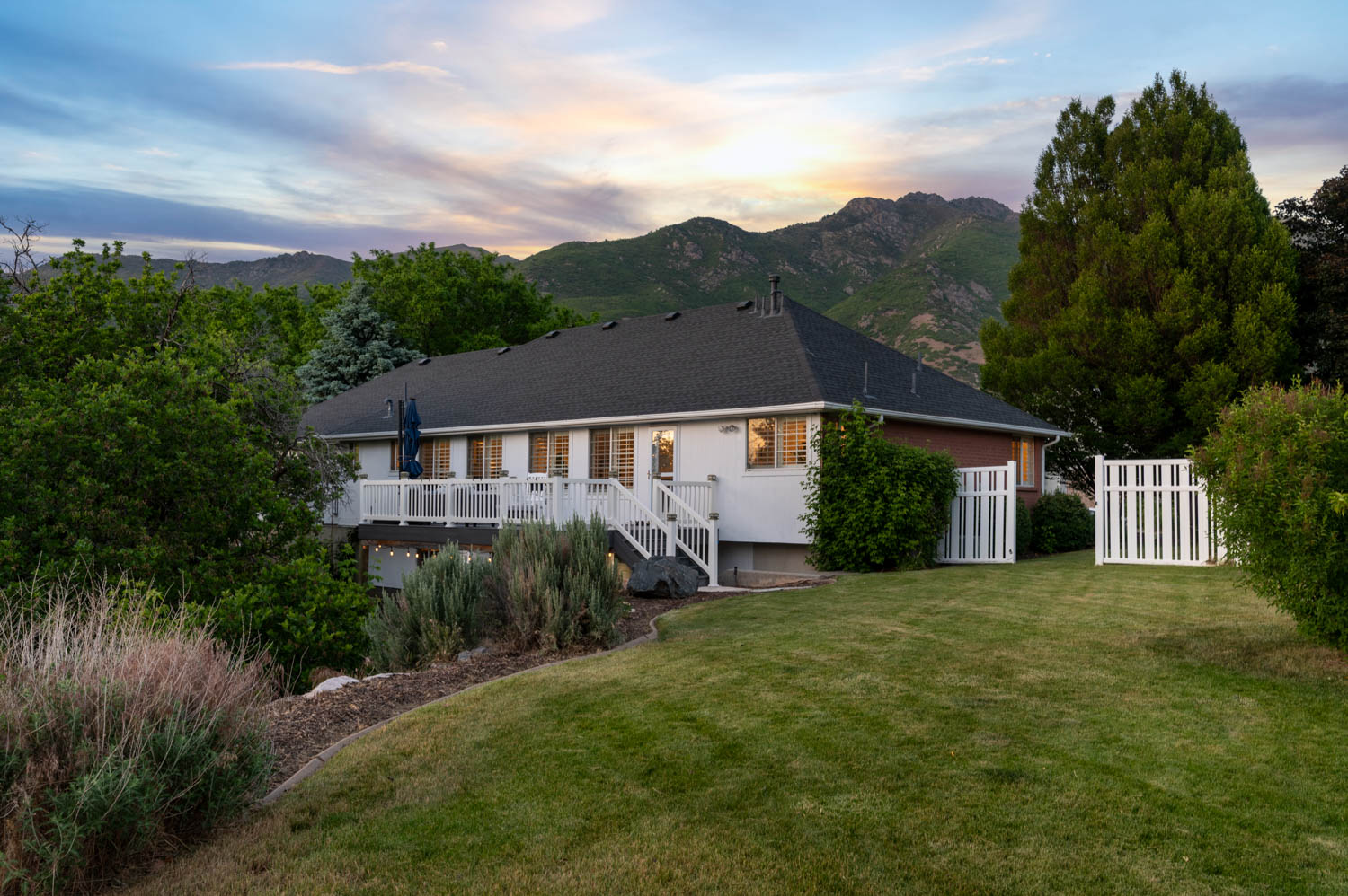 Expansive backyard featuring a manicured lawn, established landscaping, and a multi-level deck with white railings