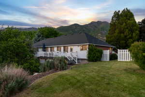 Expansive backyard featuring a manicured lawn, established landscaping, and a multi-level deck with white railings