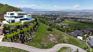 Contemporary multi-level residence featuring expansive windows, an infinity-edge pool, and a tiered landscaped yard with mature plantings and rock formations