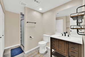 Bathroom featuring a dark wood-finish vanity with a white countertop and integrated sink, a glass-enclosed shower with gray tiled walls, and white paneled doors