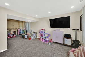 Spacious room featuring neutral carpeting, recessed lighting, and a wall-mounted display