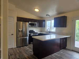 Modern kitchen featuring dark wood cabinetry, stainless steel appliances, and light-toned countertops
