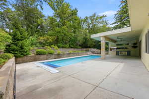 Expansive concrete patio with an integrated swimming pool and stone retaining walls