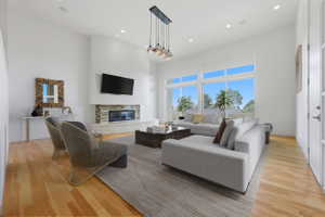 Spacious living area featuring high ceilings, light wood-finish flooring, and ample natural light from extensive windows