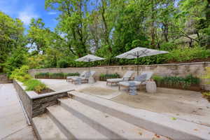 Multi-level concrete patio with integrated planter boxes and retaining walls, surrounded by mature trees