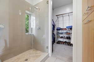 Glass-enclosed shower with subway tile surround, mosaic tile floor, and a window for natural light