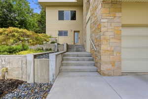 Split-level residence featuring stone and siding exterior, concrete staircase, and integrated garage