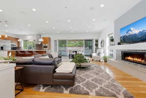 Open-concept living space featuring wood-finish flooring, a linear fireplace with mosaic tile surround, and a wall-mounted television