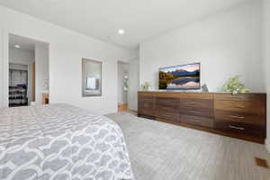 Expansive room featuring light gray carpet, recessed lighting, and a built-in wood-finish dresser with multiple drawers